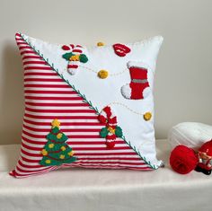 a decorative pillow with christmas decorations on it next to a red and white santa hat