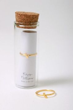 a bottle with a gold ring on it next to a cork lid and white background