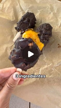 a person holding a donut with chocolate and orange on it