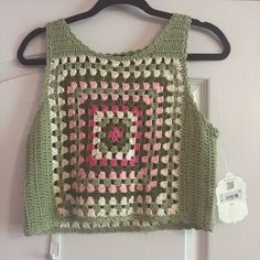 a green crocheted top hanging on a hanger next to a white door