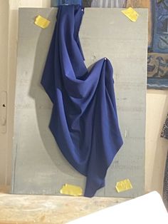 a blue scarf hanging on the wall next to a piece of paper with yellow sticky notes all over it