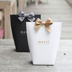 two black and white boxes with bows on them sitting on a wooden table next to each other