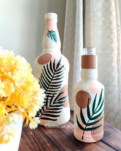 two bottles sitting on top of a wooden table next to a vase with yellow flowers