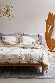 a bed with white sheets and purple pillows