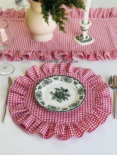 the table is set with red and white place mats, silverware, and flowers