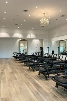 rows of treadmills in a gym with mirrors and chandelier above them