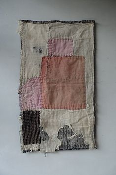 an old piece of cloth with different colored patches and holes in it on a white surface