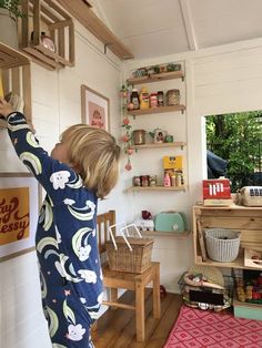 a little boy that is standing up in a room with some shelves and toys on the wall