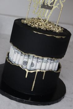 a black and gold cake with money on top