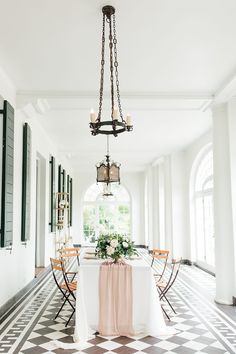 a dining room with tables and chairs in the center, chandelier hanging from the ceiling