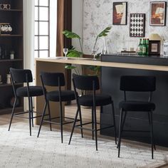 three black bar stools sitting in front of a counter