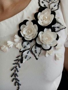 a woman wearing a white shirt with black and white flowers on the back of it