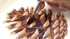 a person using a brush to paint a pine cone