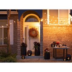 some pumpkins are on the ground in front of a house with lights strung over it