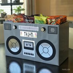 a radio shaped box with snacks in it on a table next to a plant and window