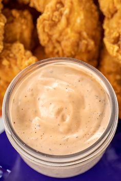 a blue plate topped with fried chicken next to a cup of ranch dressing on top of it