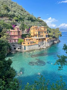 some houses are on the side of a cliff by the ocean with clear blue water