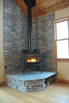 a wood burning stove sitting inside of a living room next to a wooden floor and window