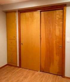 an empty room with wooden doors and hard wood flooring