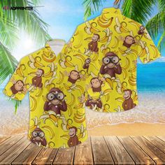 a yellow shirt with monkeys and bananas on it, sitting in front of the ocean