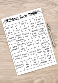 a printable fantasy book bingo game on a wooden table with a pen and paper