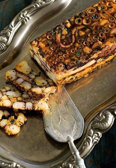 there is a silver tray with food on it and a knife next to the platter