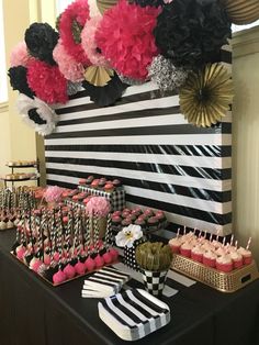 a black and white table topped with lots of cupcakes next to desserts