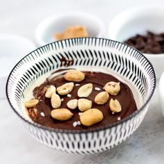 a bowl filled with chocolate pudding and nuts next to bowls of cookies on the table