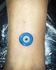 a small blue and white tattoo on the side of a woman's leg, with an eyeball in the center