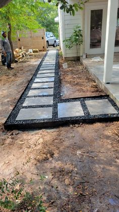 a walkway made out of black and white tiles in front of a house