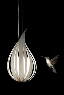 a hummingbird flying next to a white light fixture in the dark sky with a bird on it's side