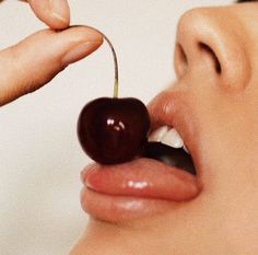 a woman is eating a cherry with her tongue