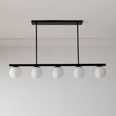 an overhead light fixture with five white balls hanging from it's black metal frame