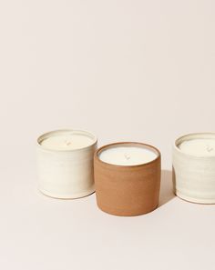 three white and brown candles sitting next to each other