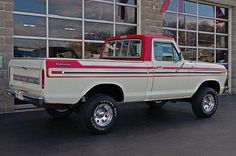 a red and white pickup truck parked in front of a building with large windows on it's side