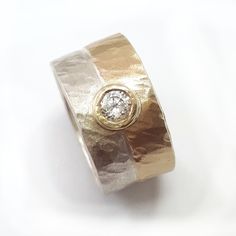 "This engagement ring is both glamorous and unique. The band has a sterling silver base with a sheet of 10k gold soldered on top and hammered. The hammered texture makes this simple ring stand out. The ring is set with a Cubic Zirconia in a gold bezel. Measurements for both bands: Width: 0.42 inch / 10.5 mm Thickness: 0.06 inch / 1.5 mm The CZ ring is set with a 0.16 inch / 4 mm cubic zirconia. Sizes: This listing is for sizes 4-13. If a different size is needed, please contact us. When ordering Wide Band Diamond Ring With Single Diamond, Gold Wide Band Ring With Tension Setting, Wide Band Promise Ring With Single Diamond, Anniversary Ring With Single Diamond On Wide Band, Anniversary Rings With Single Diamond In Wide Band, Anniversary Wide Band Ring With Single Diamond, Anniversary Diamond Ring With Bezel Setting Wide Band, Anniversary Wide Band Ring With Tension Setting, Anniversary Ring With Bezel Setting And Wide Band