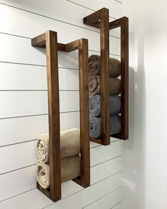 two wooden shelves holding towels and folded towels in a bathroom with white shiping walls