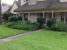 a house that has some bushes in front of it and grass on the ground next to it