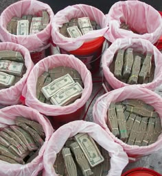 several buckets filled with bundles of money sitting on top of a table next to each other