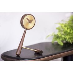 a clock sitting on top of a table next to a plant