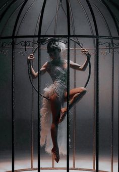 a woman is standing in a cage with feathers