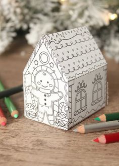 an ornament shaped like a house next to colored pencils and a christmas tree