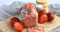 some strawberries and cookies on a cutting board next to a jar of granola