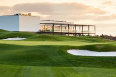 a white building sitting on top of a lush green hillside next to a golf course