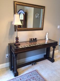 a piano sitting on top of a wooden table in front of a mirror and lamp