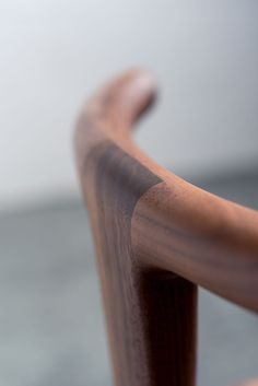 a close up view of a wooden chair with curved armrests and wood slats