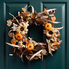 a wreath with sunflowers, leaves and pumpkins on a green front door