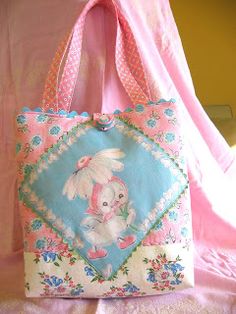 a pink and blue handbag sitting on top of a bed