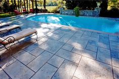 an empty swimming pool with lounge chairs around it and trees in the backround