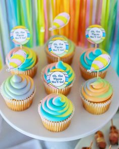 cupcakes with colorful frosting and decorations on a cake plate at a party